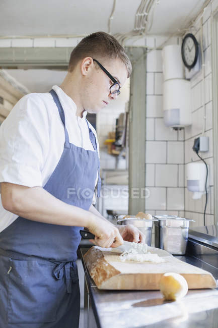 Jeune chef hacher l'oignon — Photo de stock