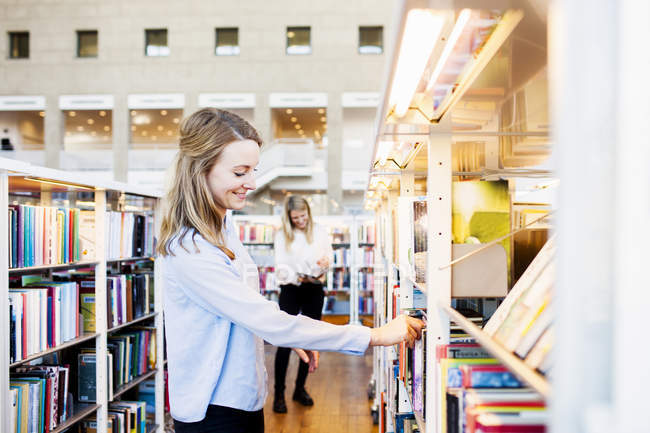 Женщина выбирает книгу в библиотеке — стоковое фото