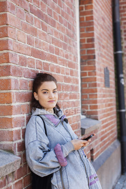 Jeune femme tenant un téléphone portable — Photo de stock