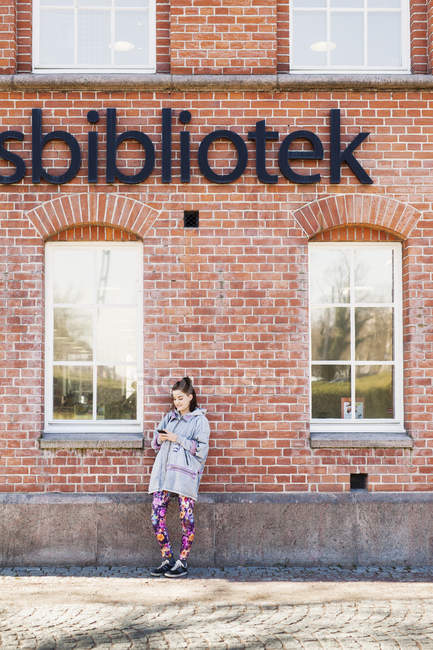 Young woman leaning on library wall — Stock Photo