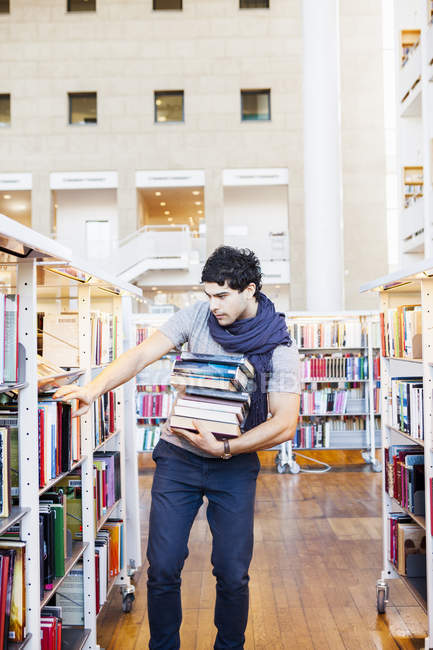 Jeune homme sélectionnant des livres — Photo de stock