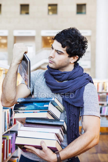 Junger Mann wählt Bücher — Stockfoto