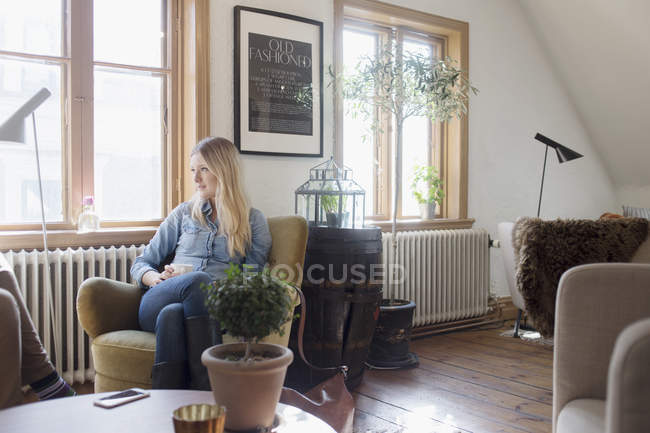 Молода жінка сидить на дивані — стокове фото