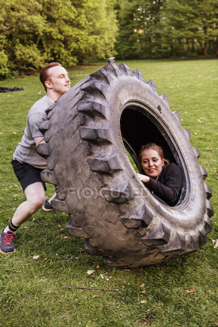 Man lifting woman sitting in tire — Stock Photo