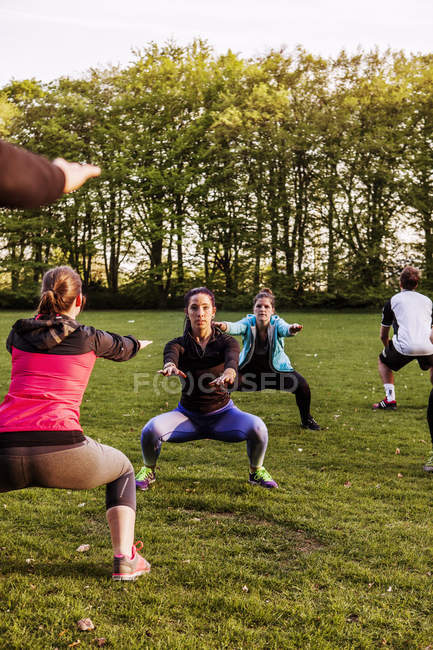 Amis faisant squats parc — Photo de stock