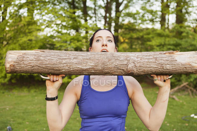 Young woman lifting log — Stock Photo