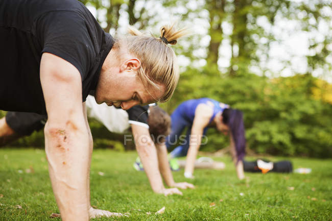 Friends doing push-ups on field — Stock Photo