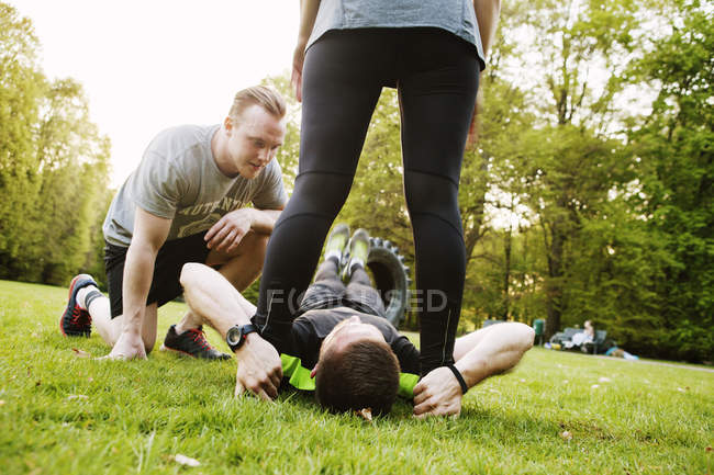 Друзі допомагають чоловікові у фізичних вправах — стокове фото