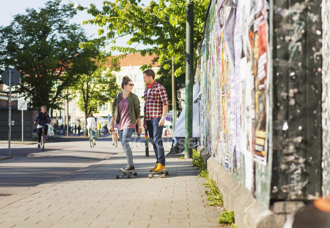 Heureux couple skateboard sur le trottoir — Photo de stock