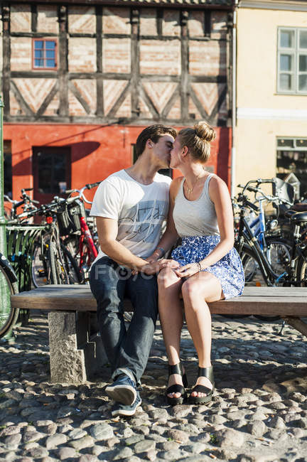 Пара целуется, сидя на скамейке — стоковое фото
