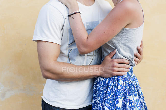 Giovane coppia che abbraccia contro muro — Foto stock