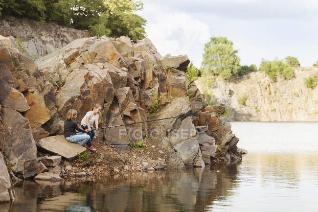 Братья и сёстры ловят рыбу на озере — стоковое фото