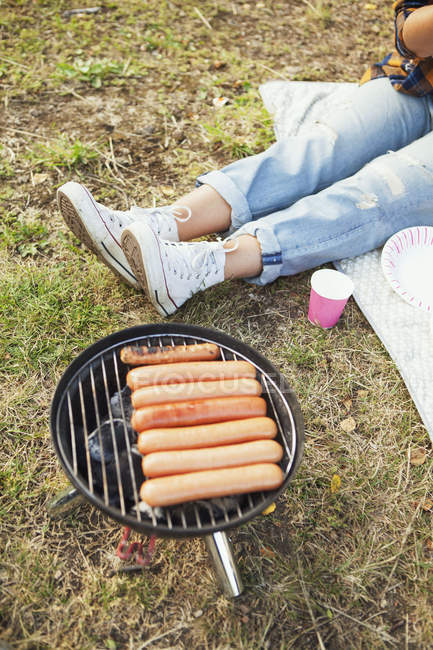 Femme assise par barbecue grill — Photo de stock