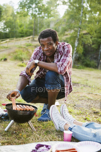 Uomo grigliare salsicce — Foto stock