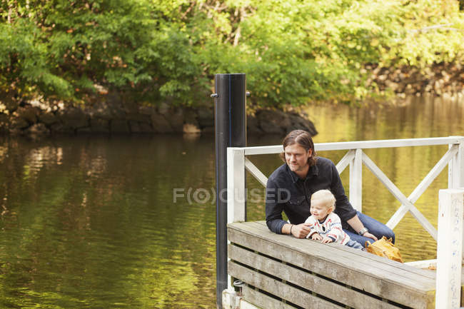 Padre e hija sentados en el muelle - foto de stock