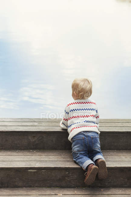 Bébé fille sur les marches en bois — Photo de stock