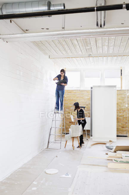 Mujeres pintando pared de madera - foto de stock