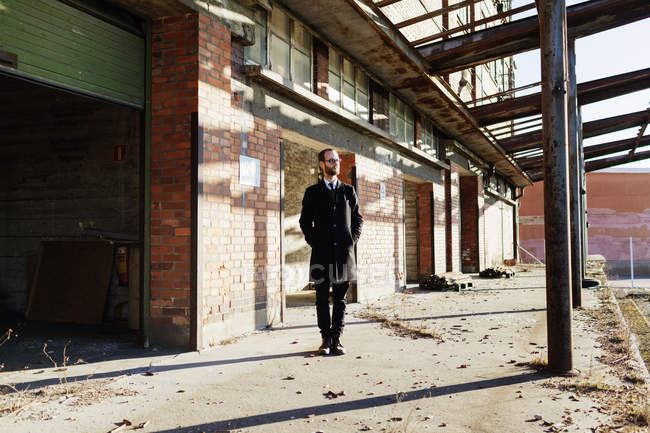 Solitario hombre de negocios frente a un edificio abandonado - foto de stock