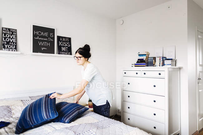 Jovem mulher fazendo cama em casa — Fotografia de Stock