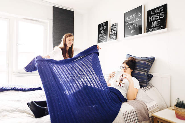 Woman putting blanket on female friend — Stock Photo
