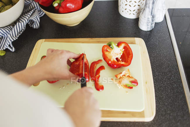 Femme hachant poivron rouge — Photo de stock