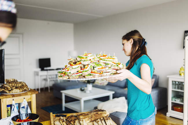 Woman carrying tray full of sandwiches — Stock Photo