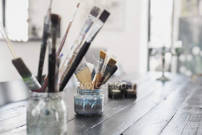 Paint brushes in containers — Stock Photo