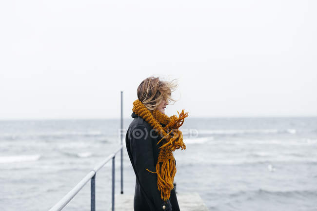 Donna che indossa sciarpa in piedi sul molo — Foto stock