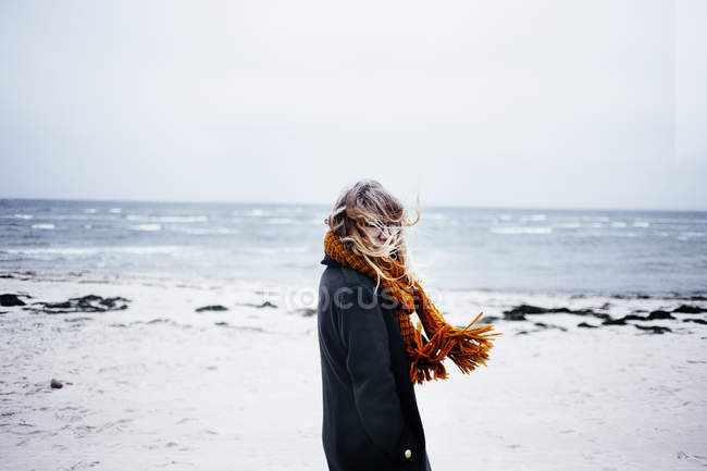 Mujer joven con bufanda en la playa - foto de stock