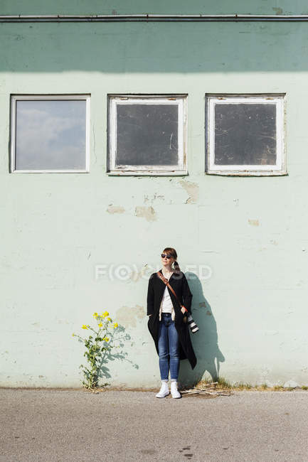 Female photographer leaning on wall — Stock Photo