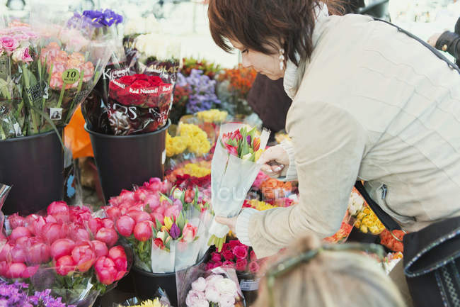 Mujer madura comprando flores - foto de stock