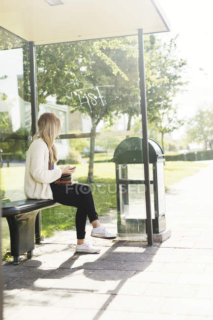 Молода жінка на автобусній зупинці — стокове фото