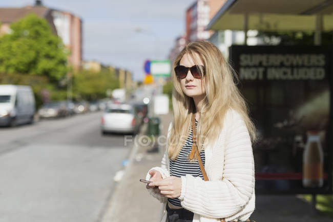 Woman wearing sunglasses holding phone — Stock Photo