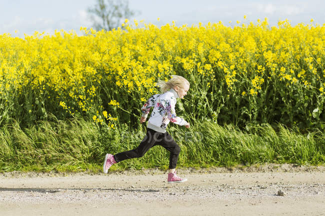 Menina correndo na estrada de terra — Fotografia de Stock