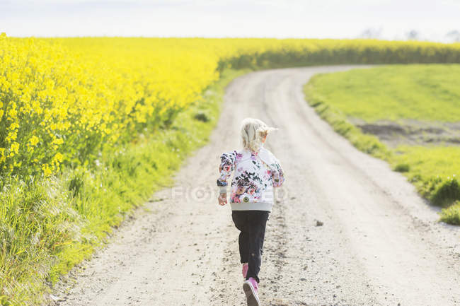 Menina correndo na estrada de terra — Fotografia de Stock
