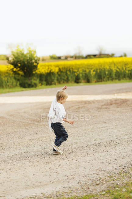 Ragazzo giocoso a piedi sulla strada sterrata — Foto stock