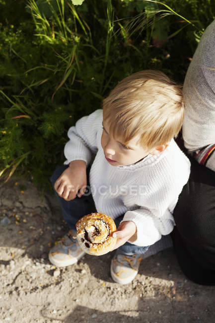 Niño sosteniendo bollo de canela - foto de stock