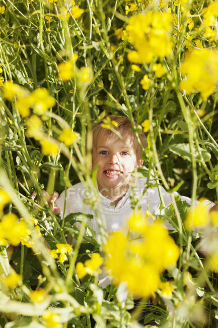 Carino ragazzo seduto in fiori — Foto stock