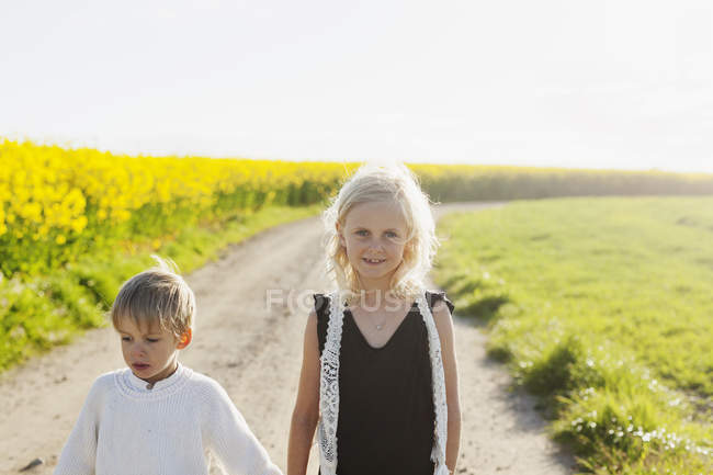 Улыбающаяся девушка, стоящая рядом с братом — стоковое фото