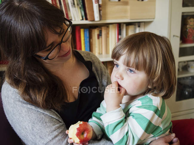 Madre con hija comiendo manzana - foto de stock