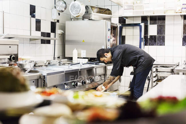 Chef di sesso maschile che lavora in cucina al ristorante — Foto stock