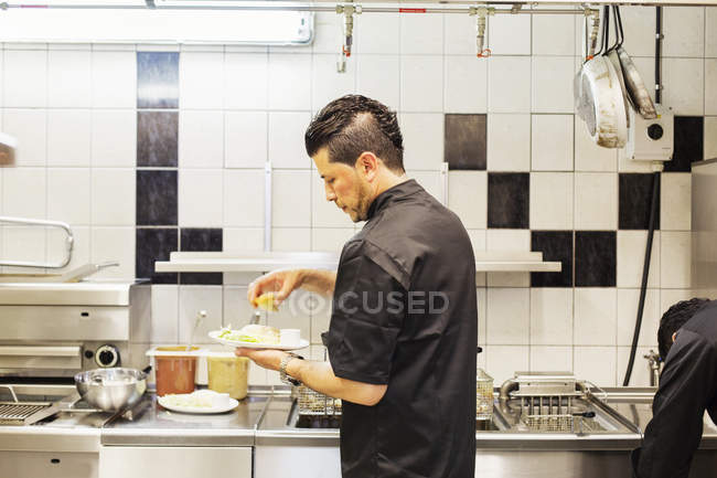 Мужчина шеф-повар, работающий на кухне в ресторане — стоковое фото