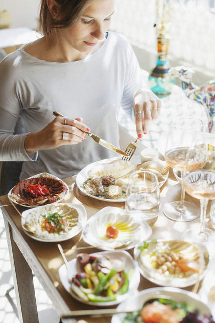 Mujer comiendo comida en la mesa en el restaurante - foto de stock