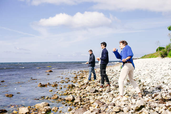Freunde werfen Kieselsteine auf Strand — Stockfoto