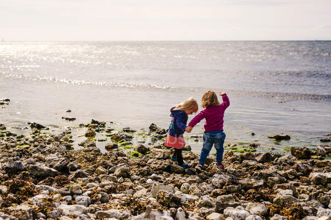 Due ragazze in piedi sulla spiaggia — Foto stock