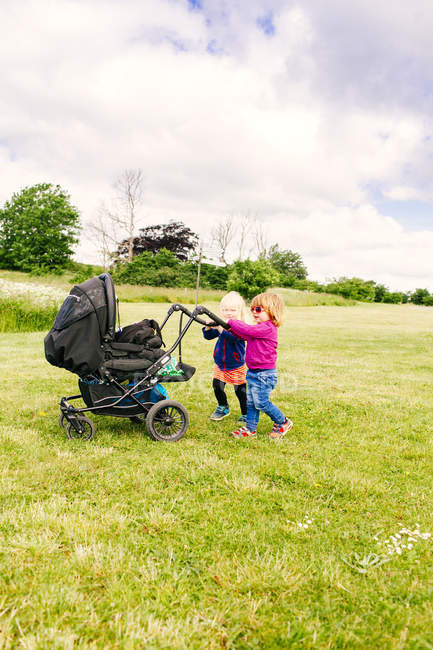 Girls playing with baby carriage — Stock Photo