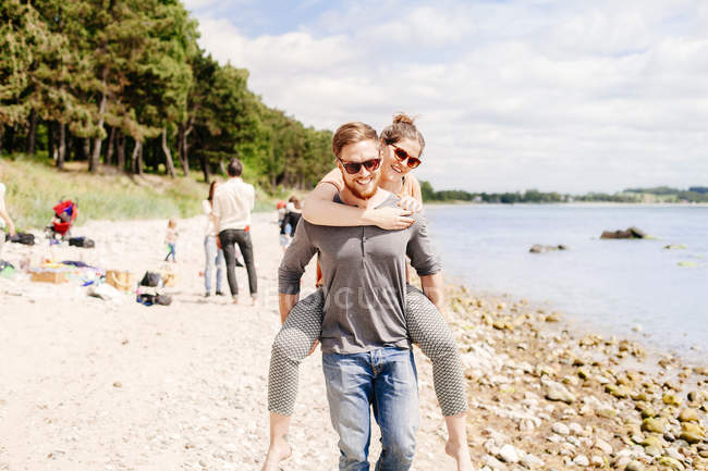 Man giving girlfriend piggyback ride — Stock Photo