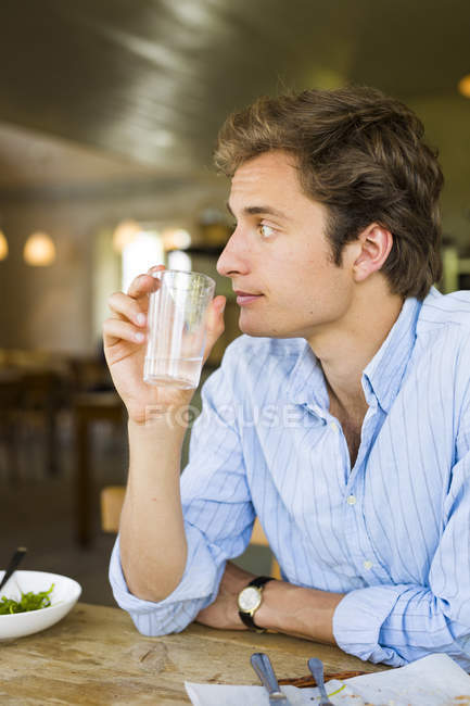 Junger Mann sitzt und trinkt Wasser — Stockfoto