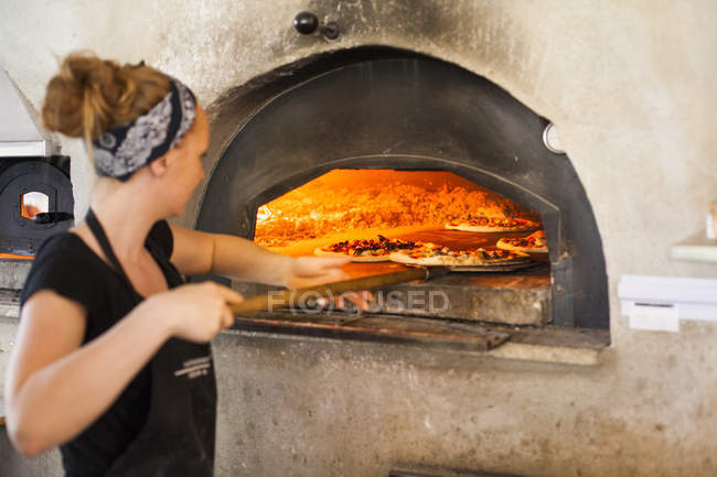 Koch legt Pizza in den Ofen — Stockfoto