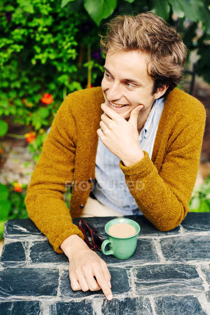 Улыбающийся молодой человек пьет кофе — стоковое фото